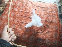 手作りの綿弓で綿を打つ